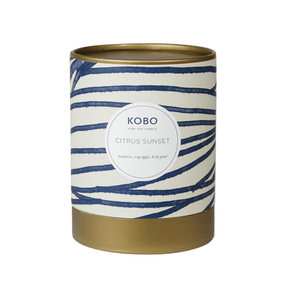Front view of Citrus Sunset Coastal Candle showcasing navy wavy stripes and gold-tone base with a plain green background