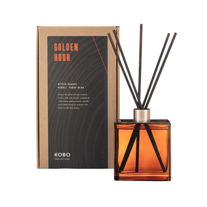 Front view of Golden Hour Woodblock Room Diffuser showcasing an amber glass bottle, black reeds, and product box